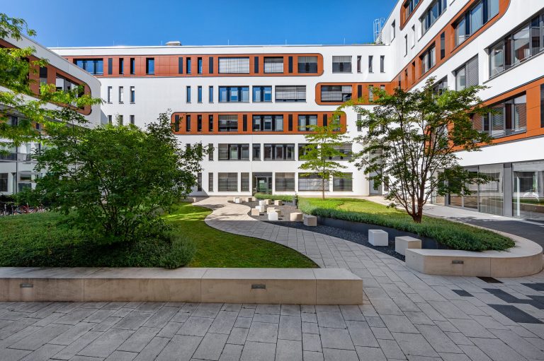 The photo shows the courtyard of a contemporary office building in Munich