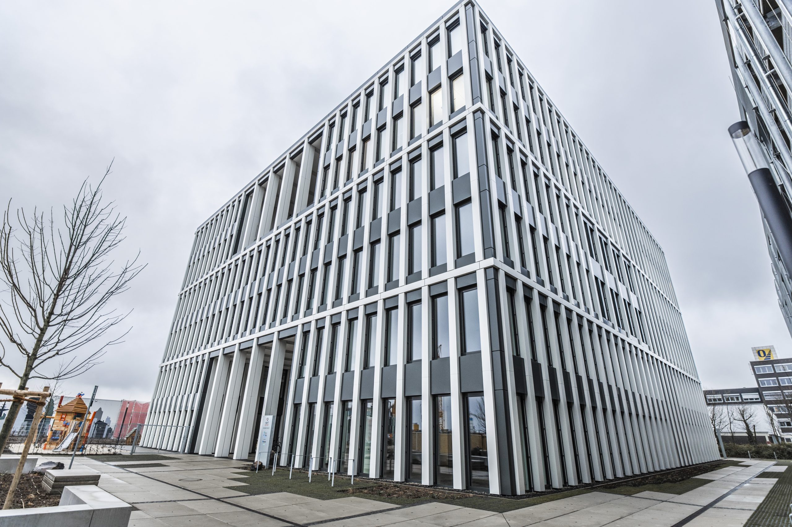 Das Foto zeigt ein neu erbautes Bürogebäude in Münster. Dessen moderne Fassade sticht hervor im Vergleich zu den anderen Gebäuden in der Umgebung